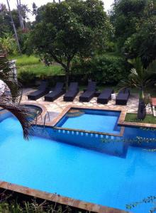a swimming pool with lounge chairs next to a resort at Villa Jaya in Lovina