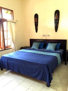 a bedroom with a bed with blue sheets and a window at Villa Jaya in Lovina