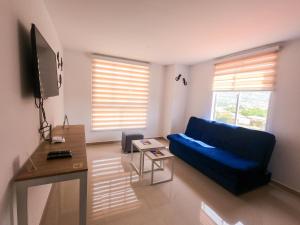 a living room with a blue couch and a tv at Apartamentos vacacionales San Gil Plaza in San Gil