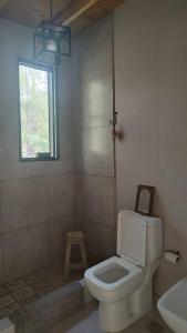 baño con aseo y lavabo y ventana en La Pausa Casa Rural en A. de la Cruz