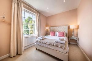 een slaapkamer met een bed met roze kussens en een raam bij The Black Lion, Long Melford in Long Melford