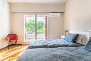 1 dormitorio con 1 cama, 1 silla y 1 ventana en Spacious renovated flat in the Athens Riviera en Atenas