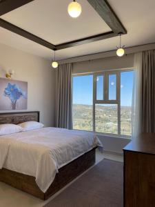 a bedroom with a large bed and a large window at منتجع جبل رثباء Rathba Mountain Resort in Suda