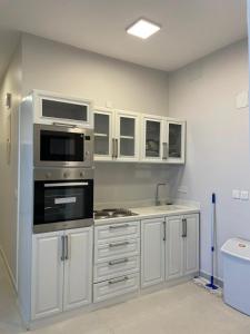 a kitchen with a stove and a microwave at منتجع جبل رثباء Rathba Mountain Resort in Suda