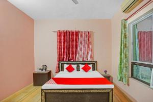 Un dormitorio con una cama con almohadas rojas y una ventana en Flagship Hotel Status en Bareilly