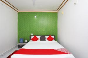 a bedroom with a bed with red pillows and a green wall at OYO Aradhya Residency in Bhubaneshwar