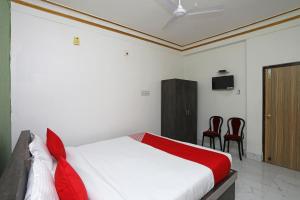 a bedroom with a bed and two red chairs at OYO Aradhya Residency in Bhubaneshwar