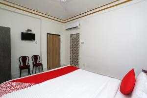 a bedroom with a bed with red pillows and two chairs at OYO Aradhya Residency in Bhubaneshwar
