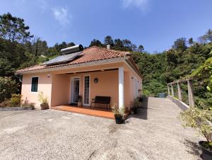een klein huis met een bank op een oprit bij Ilha & Montanha - Turismo Rural in Santana