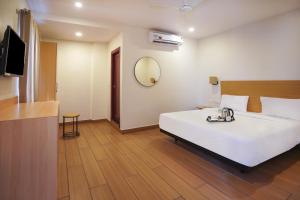 ein Schlafzimmer mit einem großen weißen Bett und einem Spiegel in der Unterkunft Townhouse The Pallagio in Visakhapatnam