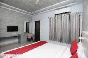 um quarto com uma cama, uma secretária e uma televisão em Flagship Hotel Mangalam Inn em Izatnagar