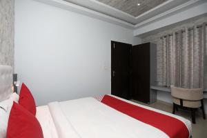 um quarto com uma cama vermelha e branca e uma secretária em Flagship Hotel Mangalam Inn em Izatnagar
