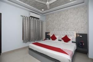 um quarto com uma cama grande e almofadas vermelhas em Flagship Hotel Mangalam Inn em Izatnagar