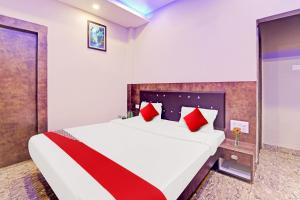 a bedroom with a large bed with red pillows at Flagship Saharsh Hotel in Patna