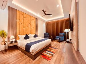 Schlafzimmer mit einem Kingsize-Bett und einem Stuhl in der Unterkunft Ganges blossam - A Four Star Luxury Hotel & Resort in Haridwar
