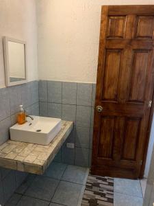baño con lavabo y puerta de madera en Chalet Casa Vacacional Riveras de Chulamar en San José de Guatemala