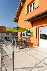 eine Terrasse mit einem Tisch, Stühlen und einem Sonnenschirm in der Unterkunft Le gite 'Humulus' in Bilwisheim