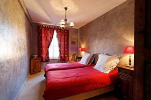 1 Schlafzimmer mit 2 Betten mit roter Bettwäsche und einem Fenster in der Unterkunft Le gite 'Humulus' in Bilwisheim