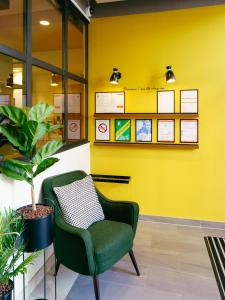 een groene stoel in een kamer met een gele muur bij Résidence services seniors CAZAM Pontoise in Pontoise
