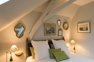 Schlafzimmer mit einem Bett mit weißen Kissen und Spiegeln in der Unterkunft La Folie Saint Julien in Saint-Julien-de-Chédon