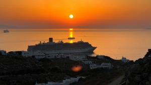 Nomia Sunset Suites Mykonos في Tagou: سفينة الرحلات البحرية في المحيط عند غروب الشمس