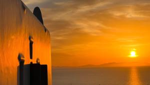 TagouにあるNomia Sunset Suites Mykonosの海と建物の夕日を望む