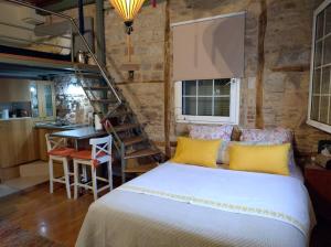 a bedroom with a bed with yellow pillows and a staircase at Mastixi in Chios