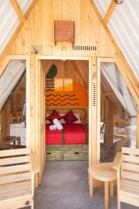 a bed in a wooden house with a red bed at Selina Atitlan in Panajachel