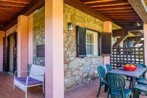Un patio con mesa y sillas y un muro de piedra. en Casa Flavia - Castiglione, en Castiglione della Pescaia