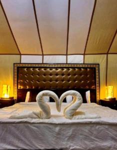 two swans laying on a bed in a room at Merzouga Sahara Camp in Merzouga