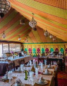 a tent with tables and chairs in a room at Merzouga Sahara Camp in Merzouga