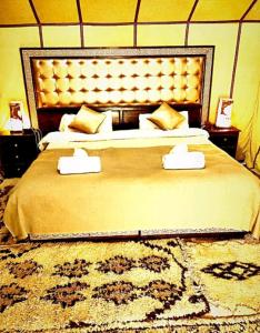 a bedroom with a large bed with a large headboard at Merzouga Sahara Camp in Merzouga