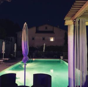 a swimming pool at night with an umbrella and chairs at A Furtezza in Soveria