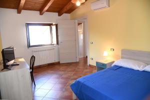 1 dormitorio con 1 cama azul y TV en B&B Villa Del Regno en Centola