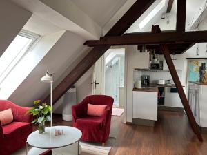 a living room with two red chairs and a table at Dachstudio im Geteviertel - citynah in Bremen