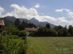 un campo con una casa y montañas en el fondo en Ferienwohnung Regauer, en Fischbachau