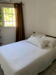 1 cama blanca en un dormitorio con ventana en Chalet Casa Vacacional Riveras de Chulamar en San José de Guatemala