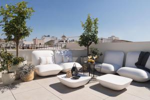 un patio con sillas blancas y mesas en un balcón en Mylu Suites by Puerta Catedral, en Sevilla