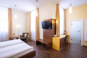 ein Hotelzimmer mit einem Bett, einem Schreibtisch und einem TV in der Unterkunft Altstadthof Freinsheim in Freinsheim