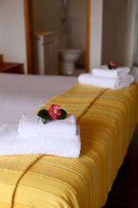 two towels with a rose on top of a yellow bed at Casas Goulart in Canto da Areia