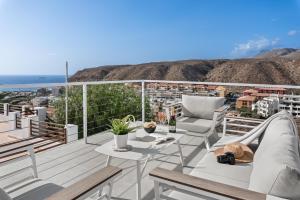 a balcony with chairs and tables and a view of the city at KARAT Villa Punta Rasca in Palm-mar