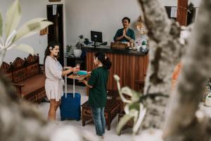 Innora Jungle Resort And Spa في نوسا بينيدا: امرأتان واقفتان في غرفة مع امرأة مع حقيبة