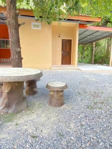 una panchina di pietra accanto a un albero di fronte a un edificio di At Sichon Resort ad Amphoe Sichon