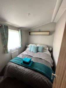 a small bedroom with a bed with blue pillows at Seton Sands St Andrews in Port Seton