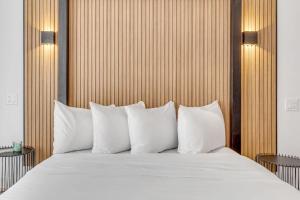 1 cama con almohadas blancas y cabecero de madera en Initial / Libre / Centre-ville de Quebec en Quebec