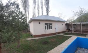 a small white house in a yard with trees at JANS дача in Chimgan