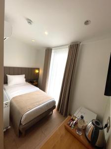 um quarto de hotel com uma cama e uma janela em Meshk Airport Hotel em Arnavutköy