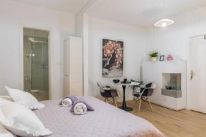 a white bedroom with a bed and a table and chairs at Guest House Tomasi in Dubrovnik