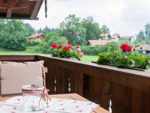 uma mesa de madeira com flores vermelhas numa varanda em Ferienwohnungen Nutz em Bad Wiessee