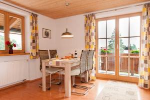 Un comedor con mesa y sillas y ventanas. en Ferienwohnungen Nutz, en Bad Wiessee